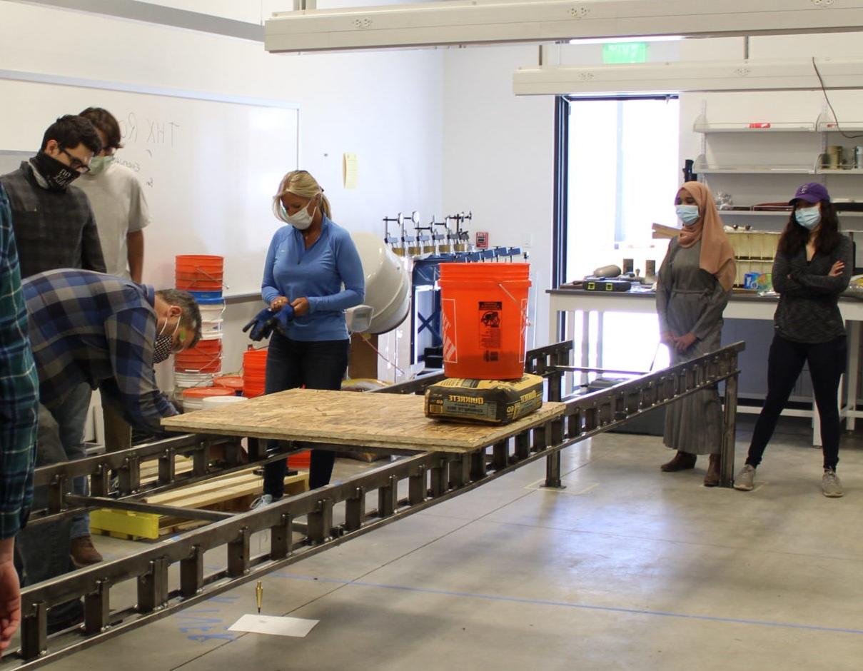 Individuals in masks working on a metal structure