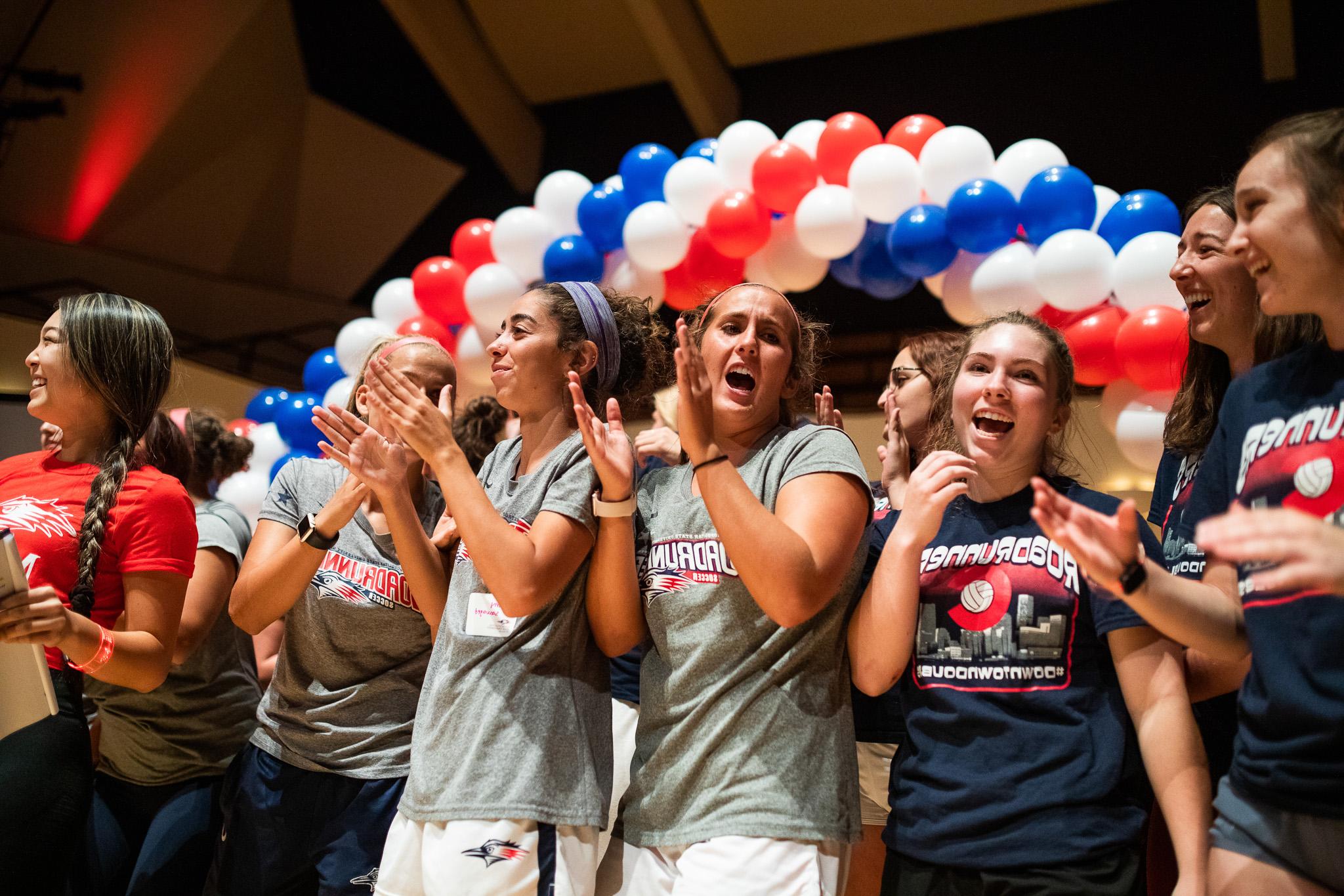 Female Volleyball team clapping and smiling during convocation ceremony