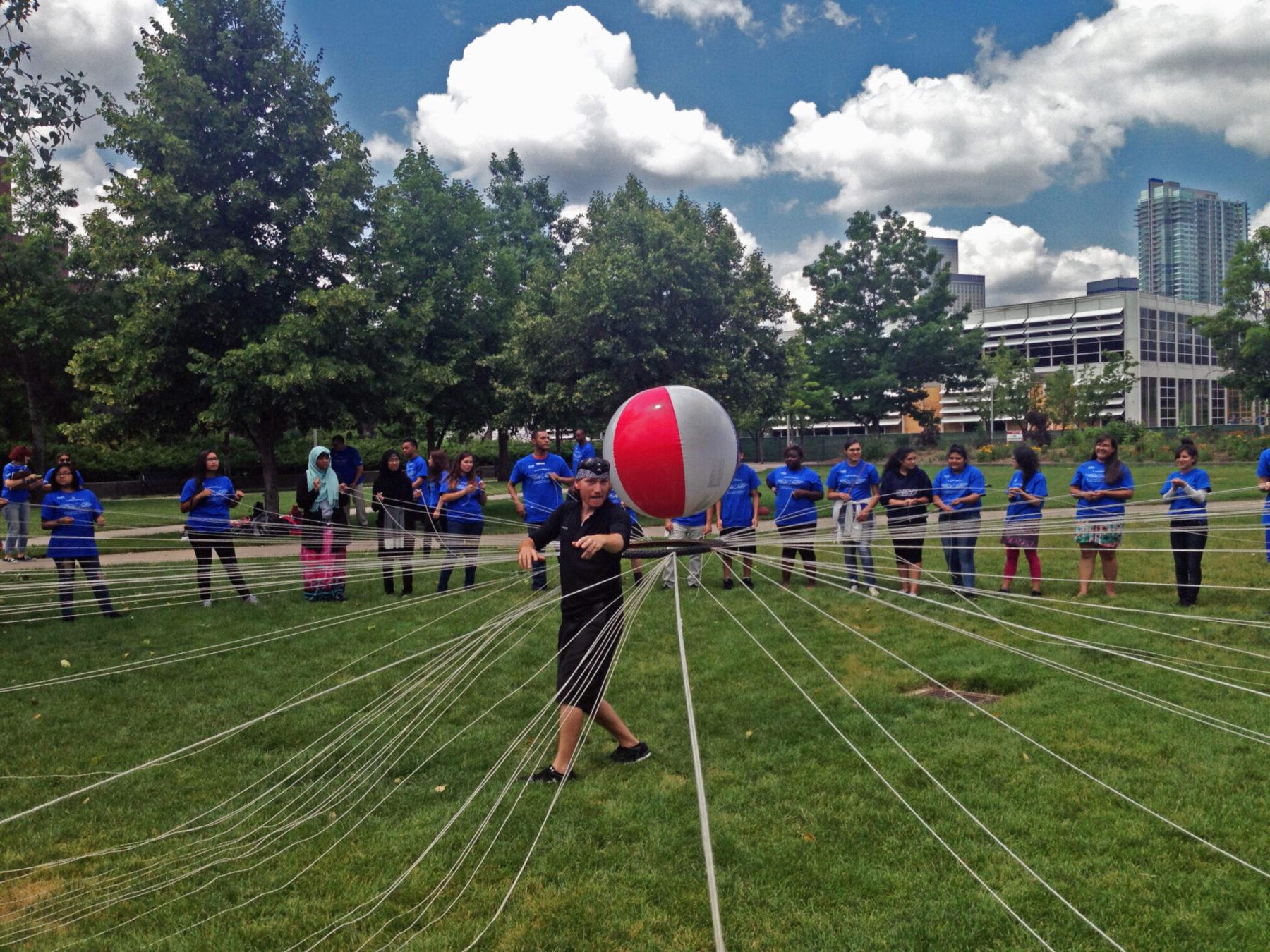 several students supporting a beach ball with string and a ring