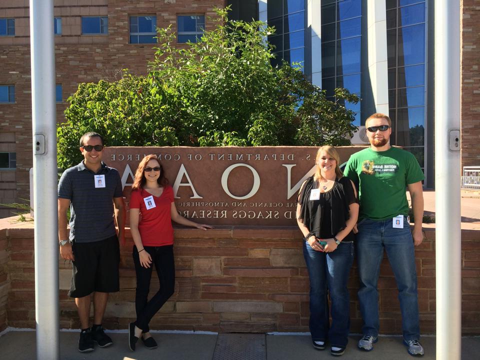 Four students standing in front of NOAA sign at NWS Boulder