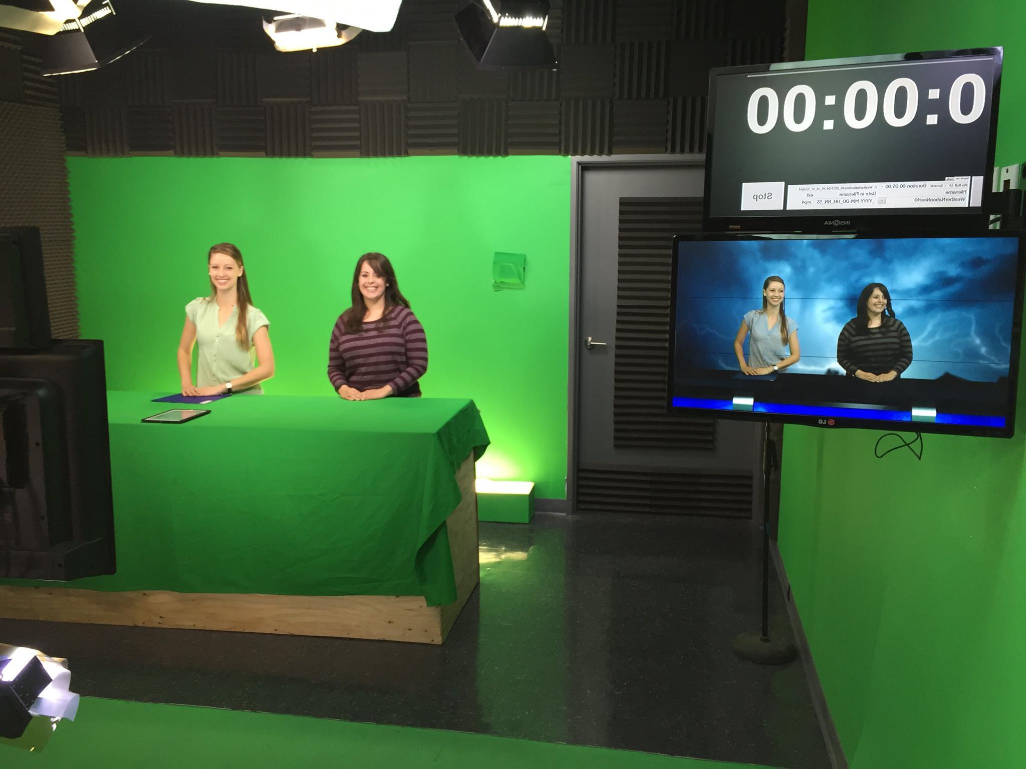 Two students in front of a green screen at a TV station