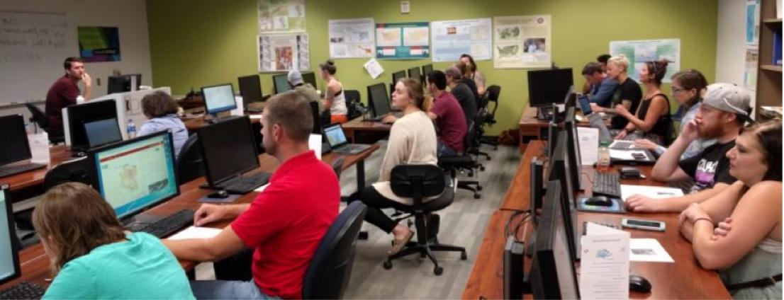 GIS workshop participants in a computer lab attentively listening to a speaker