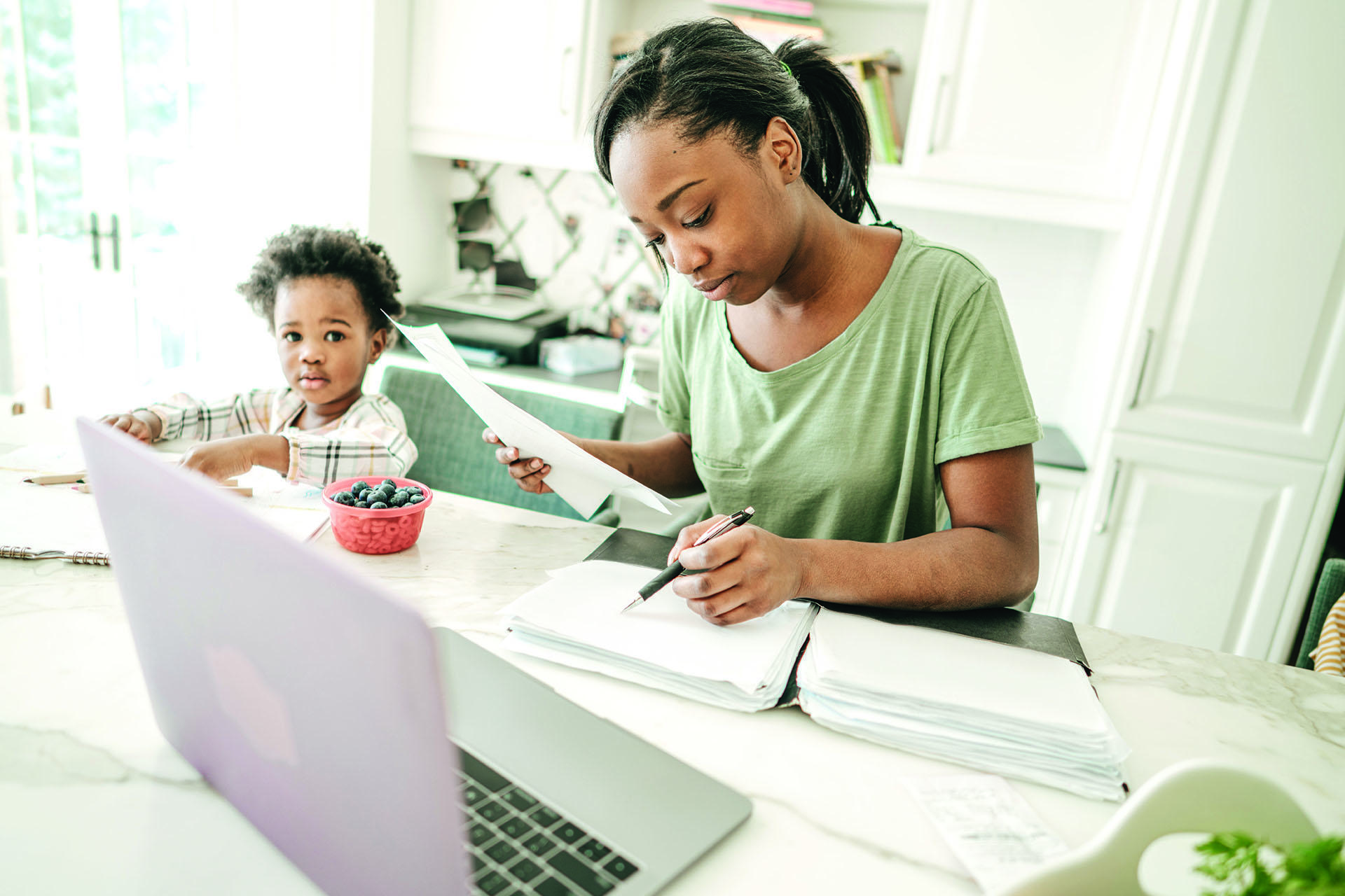 Woman studying with books and laptop, and child next to her