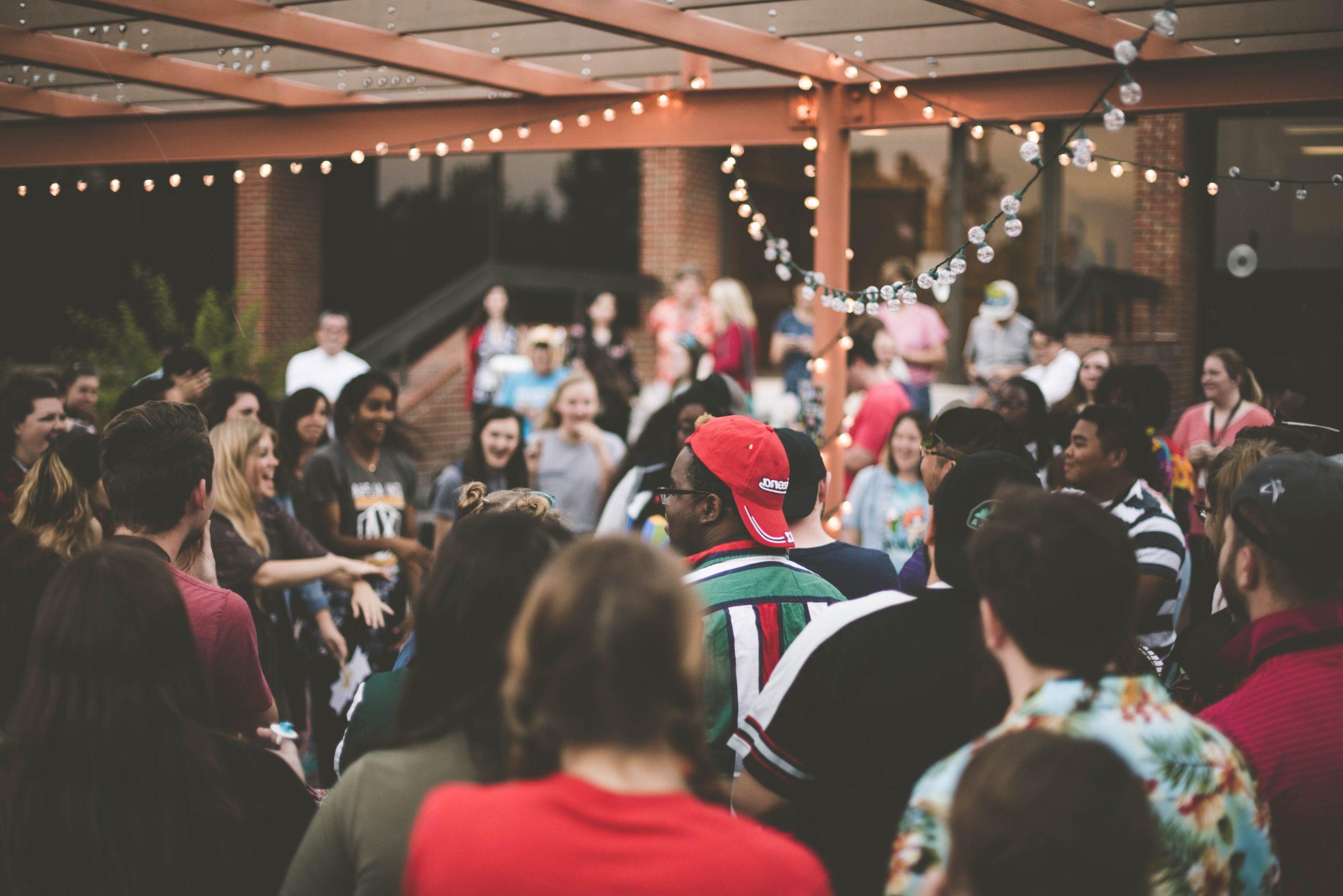 Crowd of people standing under a pergola with lights