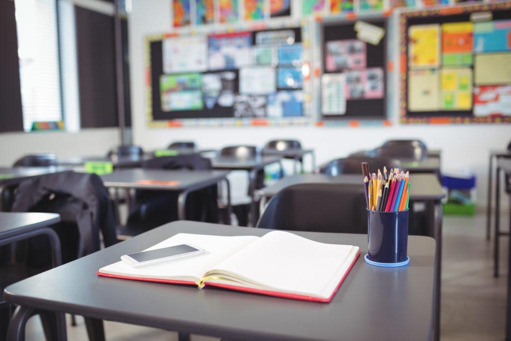 Mobile phone on open book at desk in classroom