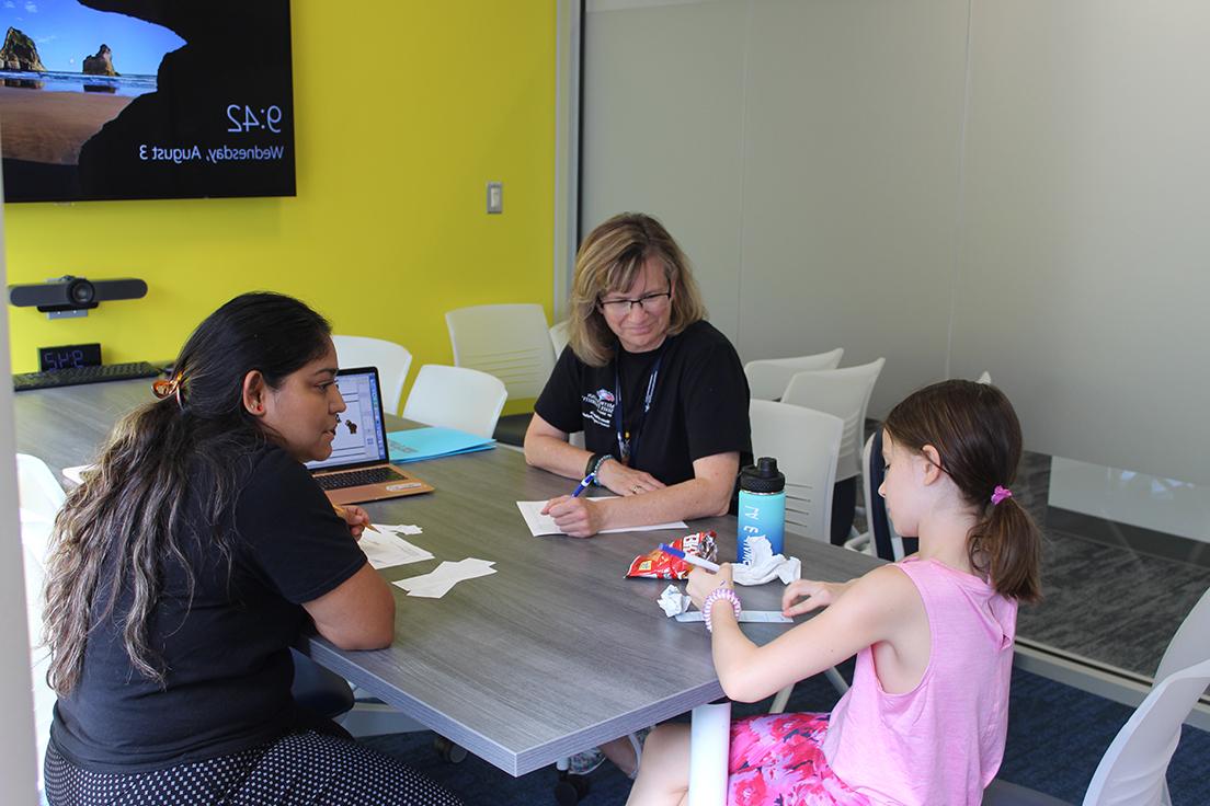 Graduate MS SLP student (right) and Clinical Educator (left) working with elementary school aged child (center)