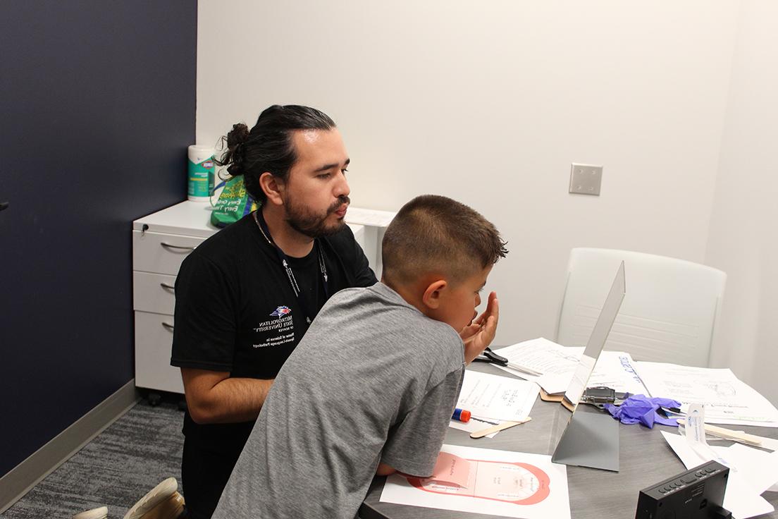 Graduate MS SLP student (right) working with elementary school aged child (left)