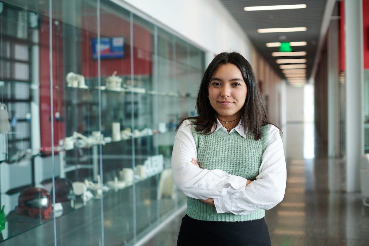 Student standing in a hallway with arms crossed.