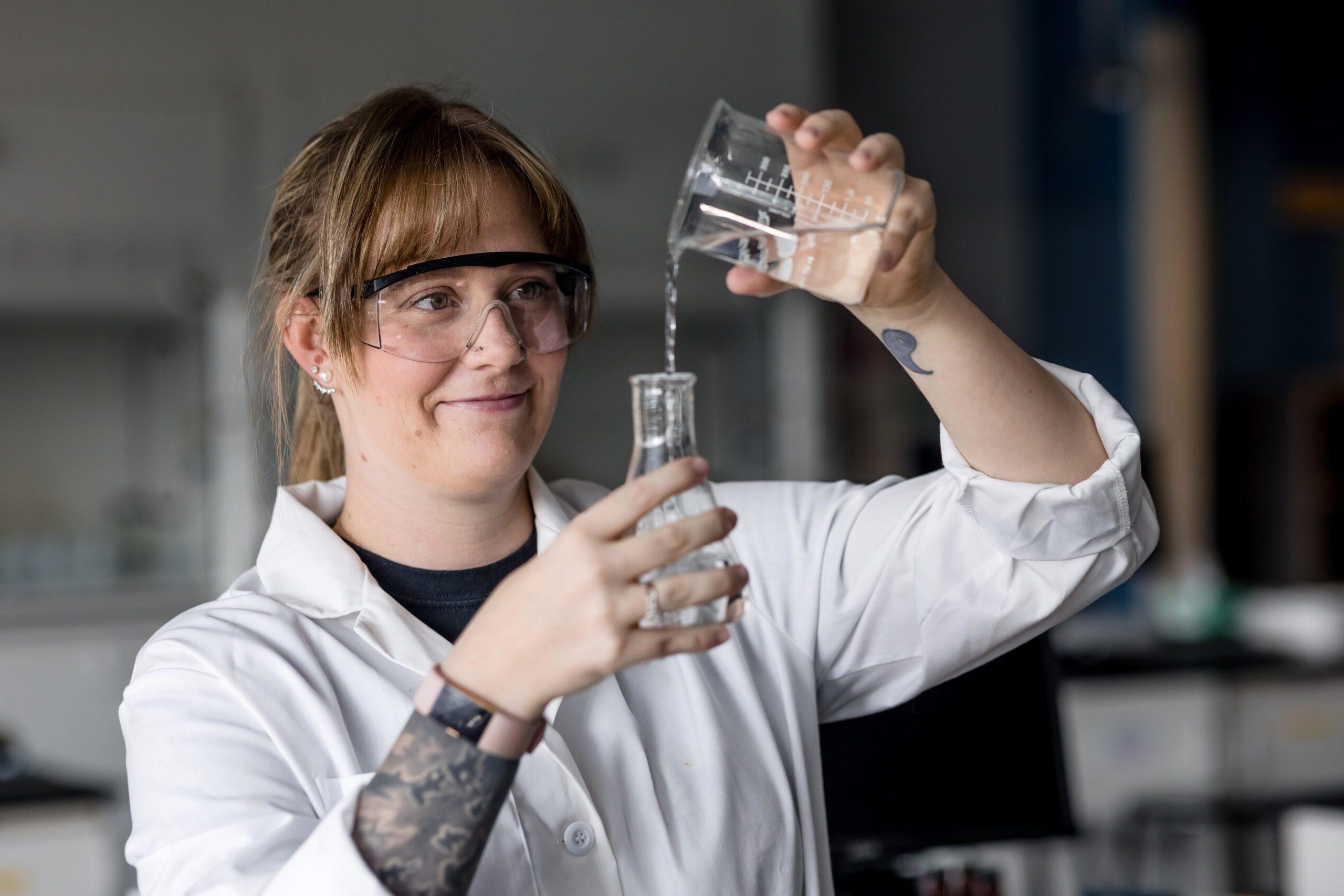 Autumn Gilmore, a chemistry and biochemistry junior at Metropolitan State University, pouring liquid from one beaker into another.