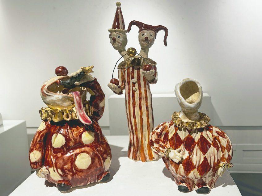 Three small clown sculptures each with different expressions, and decorated with red and gold accents.