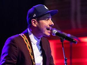 Visiting Artist Daniel French performing on a stage with a microphone