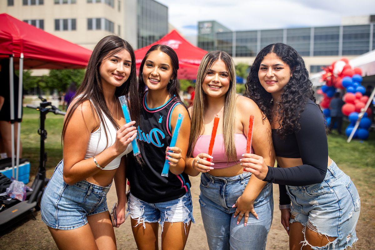 Four students pose with popsicles during an event