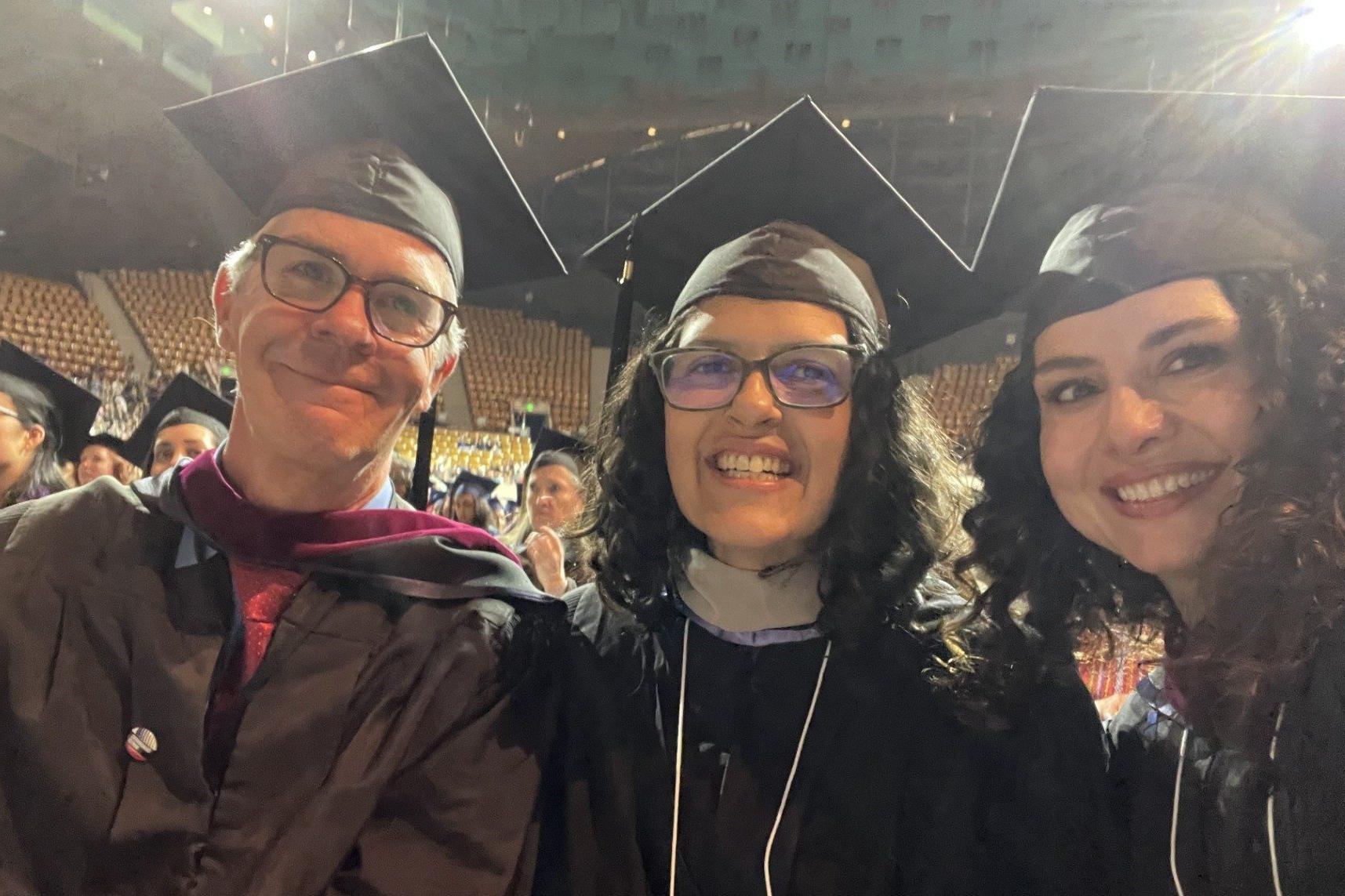 Journalism and Media Production Faculty in cap and gown (Left: Deanna Hirsch, Middle: Suree Towfighnia, Right: Joe Hammond) smile at MSU Denver Commencement