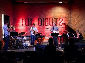 jazz musicians performing on a stage with red lights